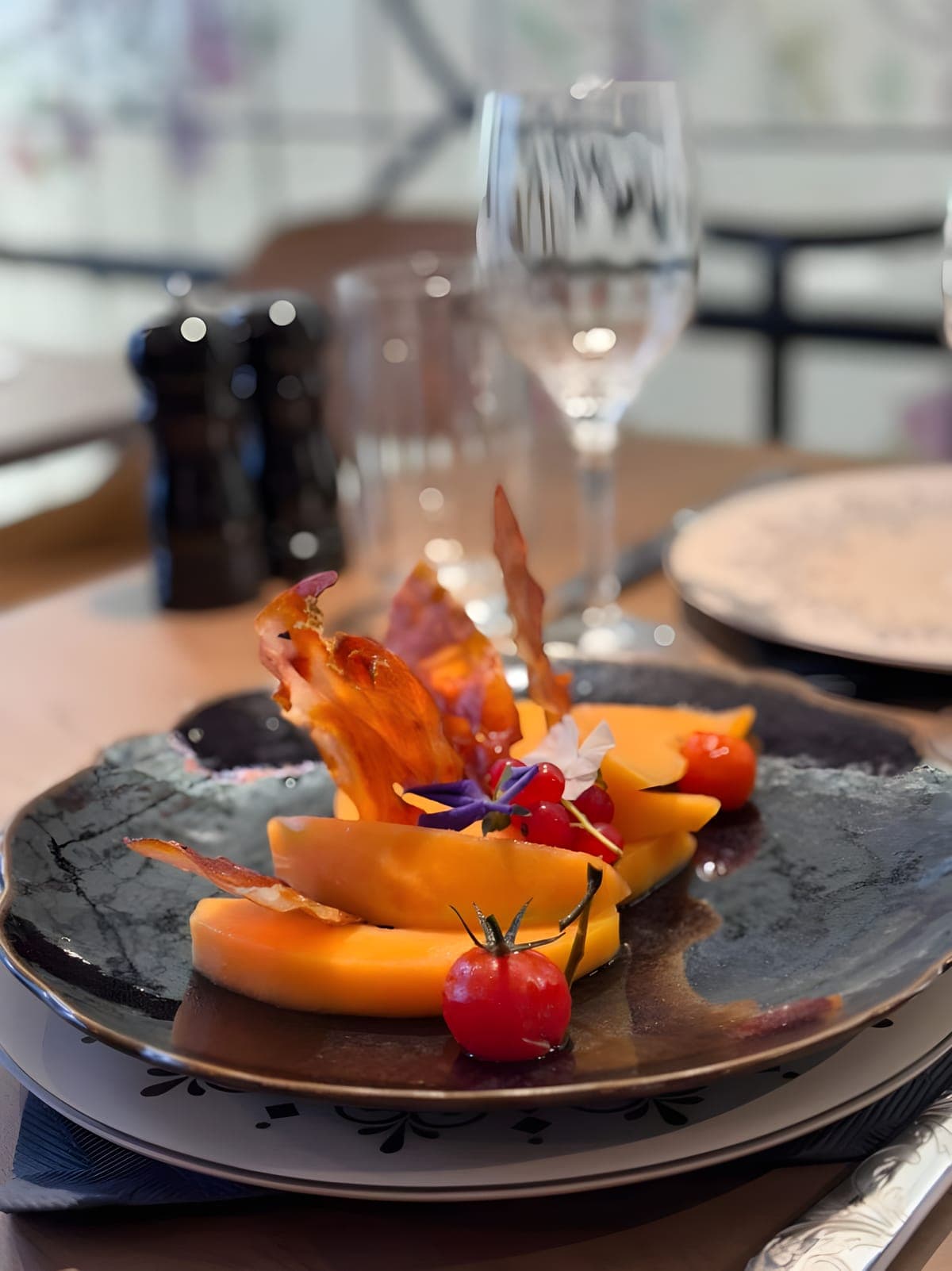Melon, crispy country ham and edible flowers, at the table